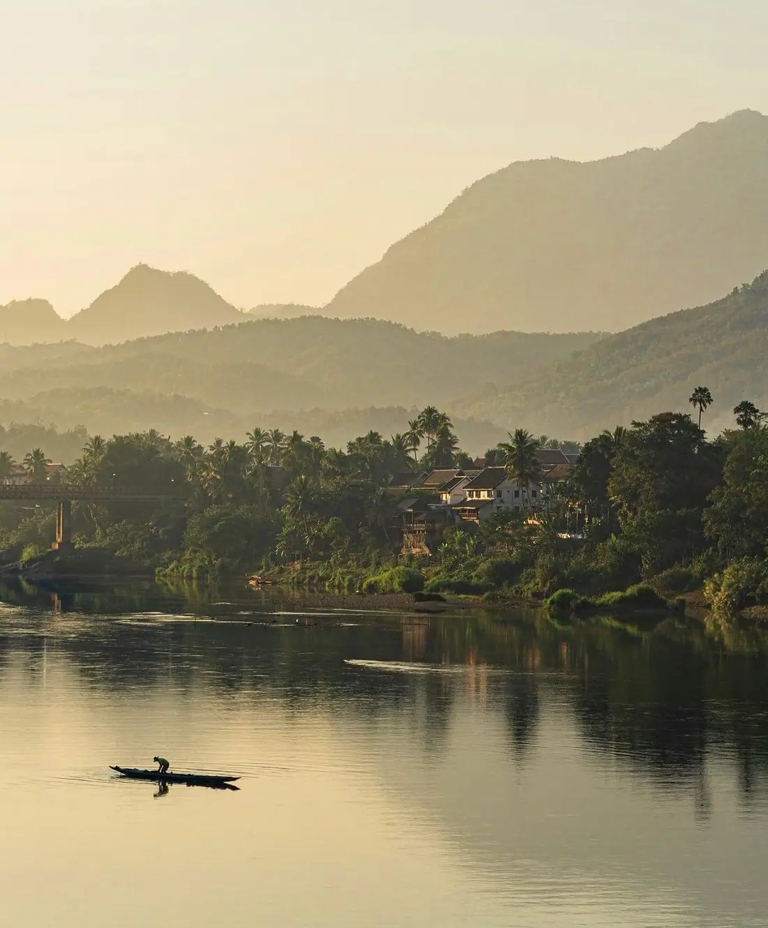 หุบเขาริมแม่น้ำยามรุ่งสาง มีเรือหนึ่งลำ และภูเขาอยู่ด้านหลัง