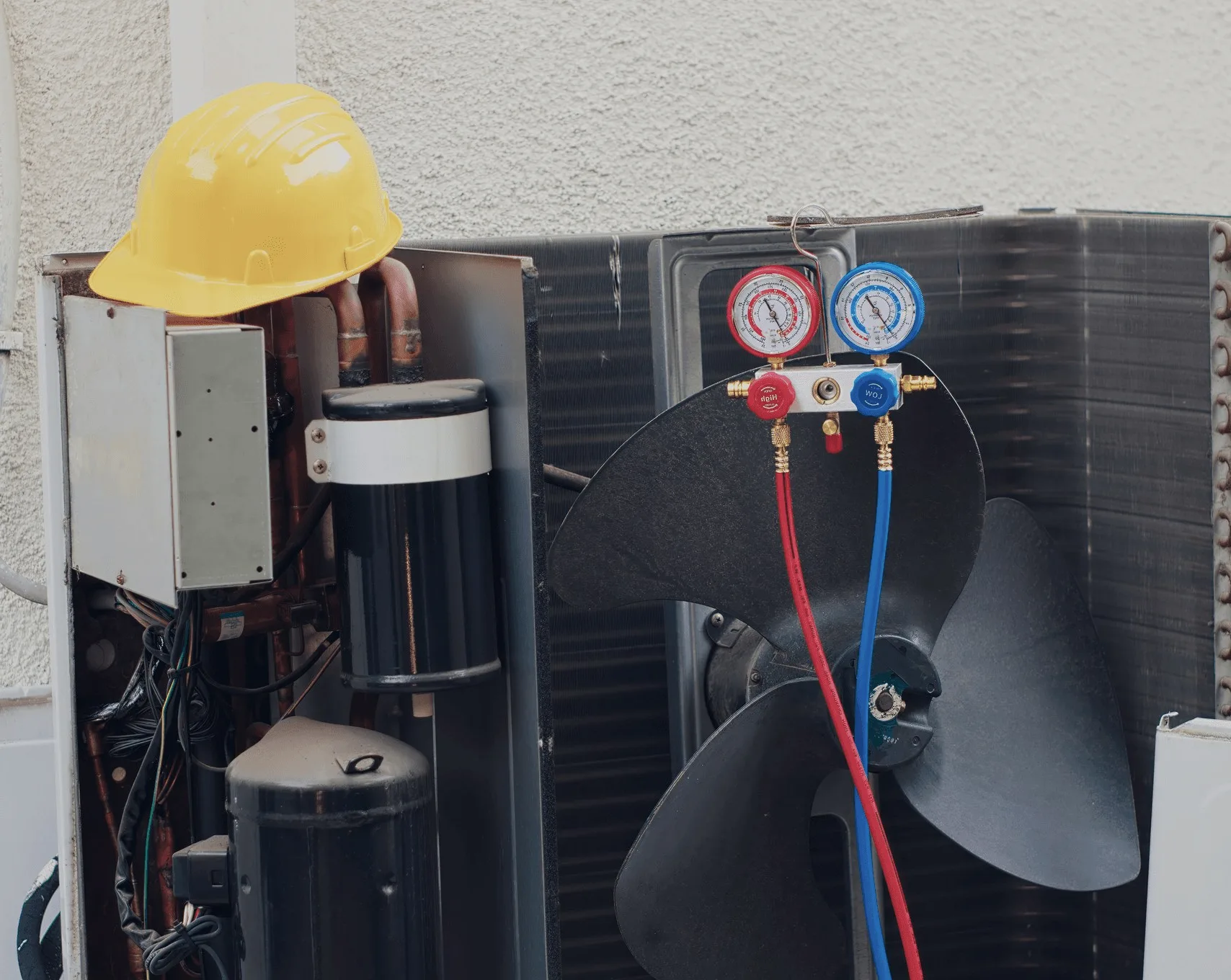 A pressure gauge set clipped to an outdoor unit.