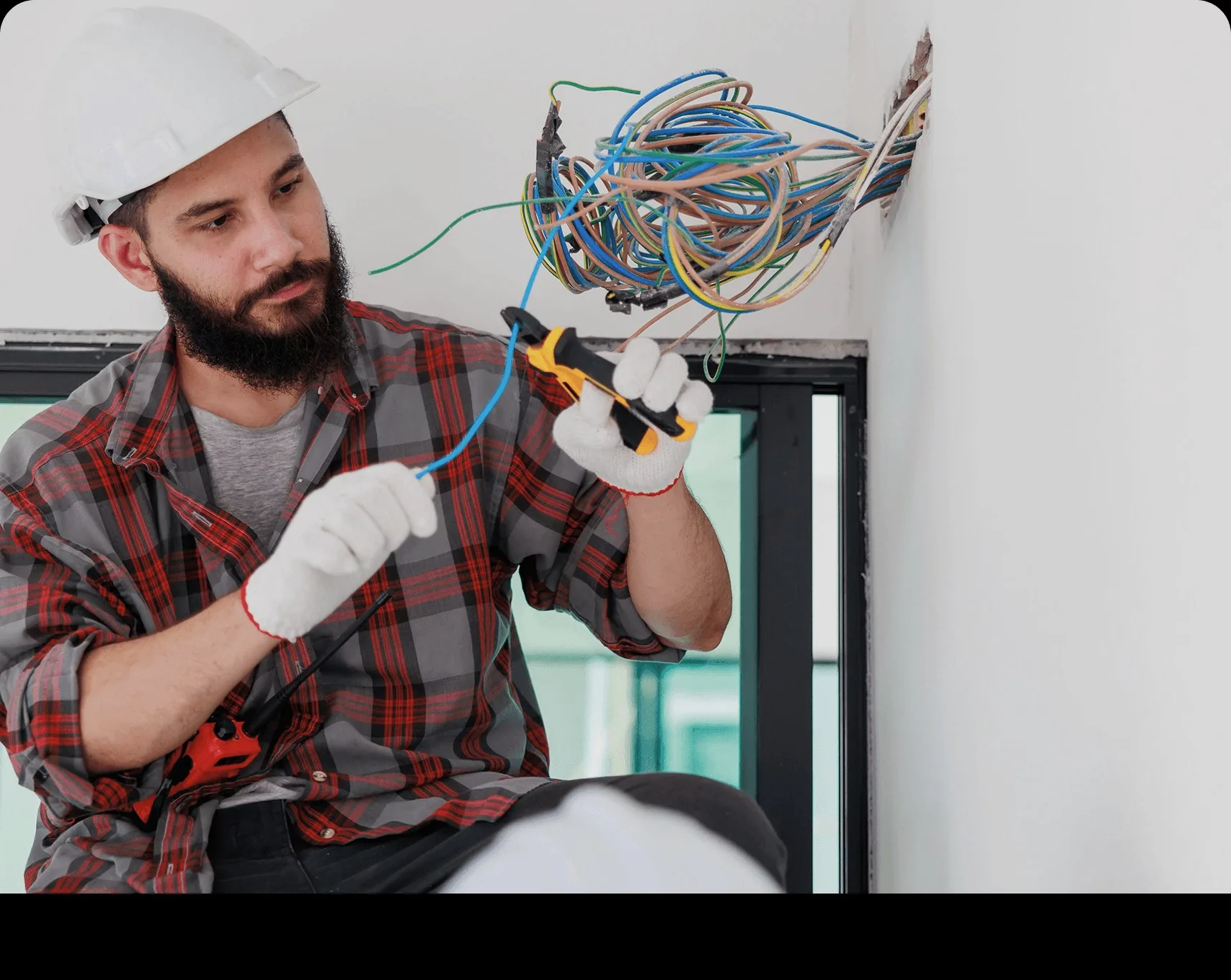 A technician stripping wires at a wall box.