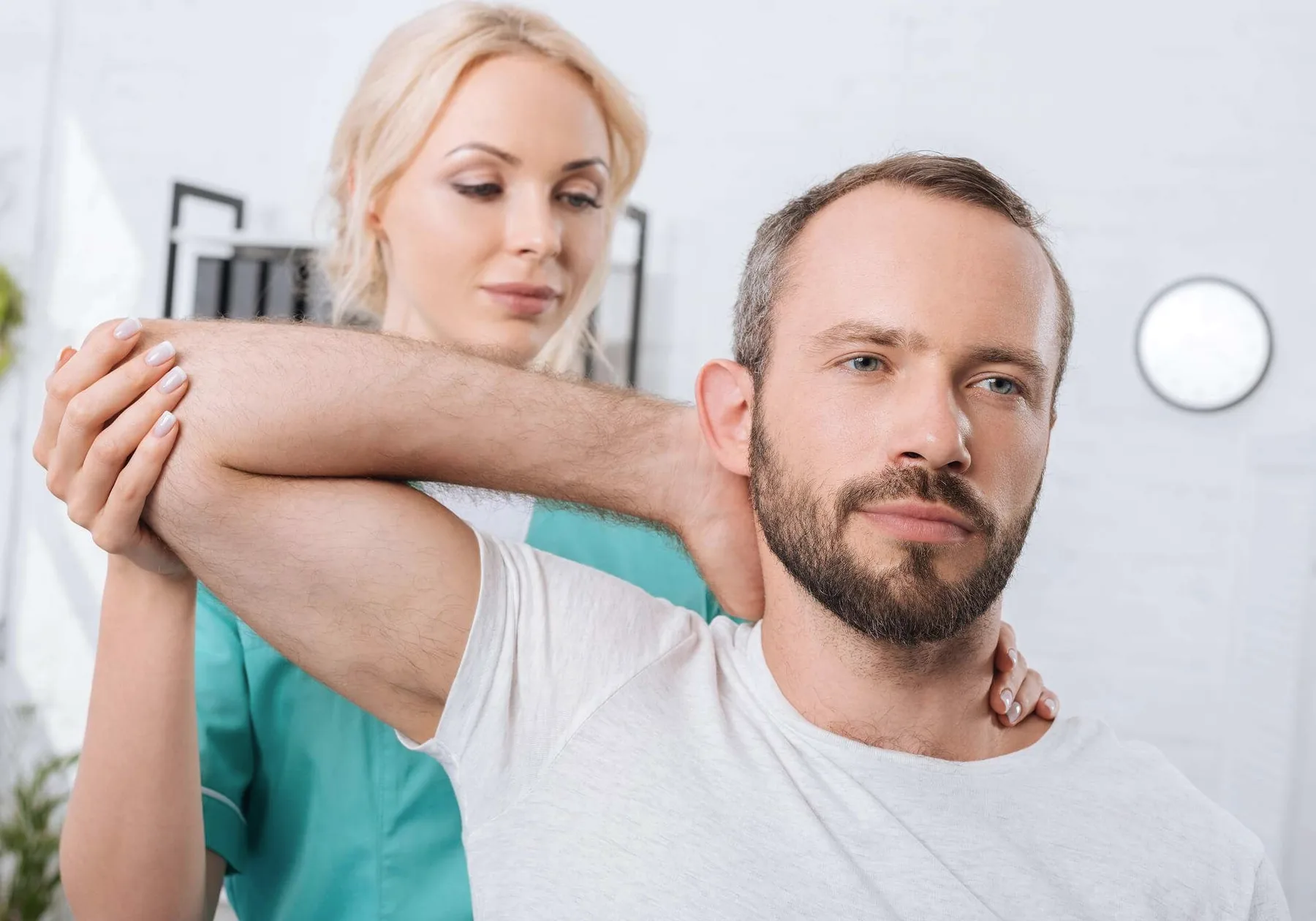 A physiotherapist stretching a man's arm across his chest.
