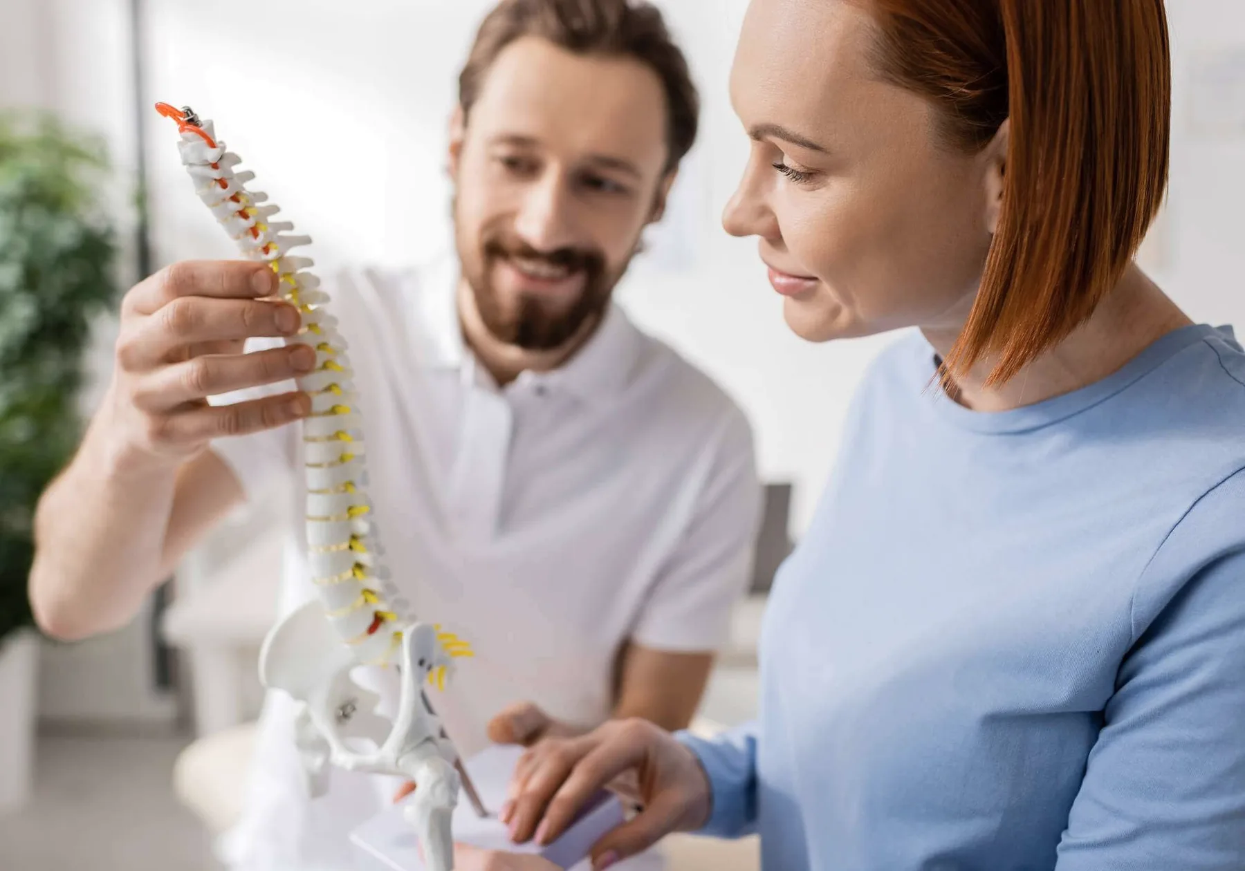 A chiropractor showing a spine model to a patient.