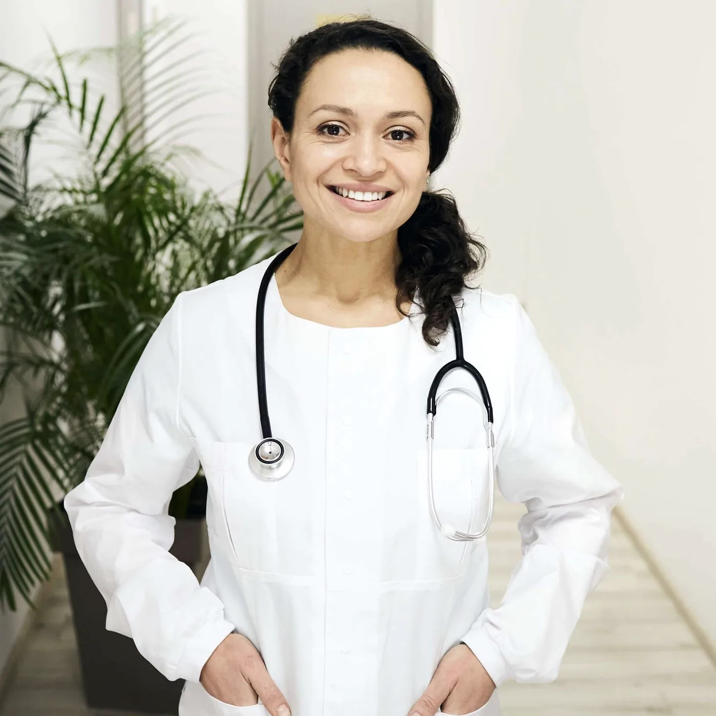 A smiling woman in a white coat with a stethoscope.