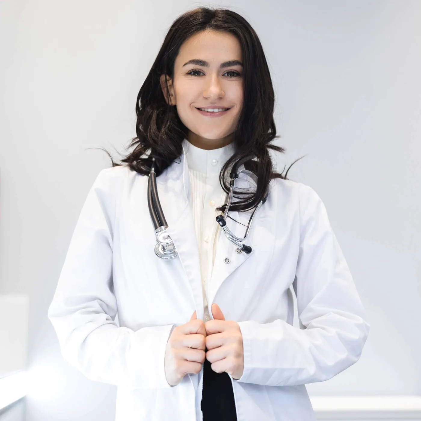 A smiling woman in a white coat.