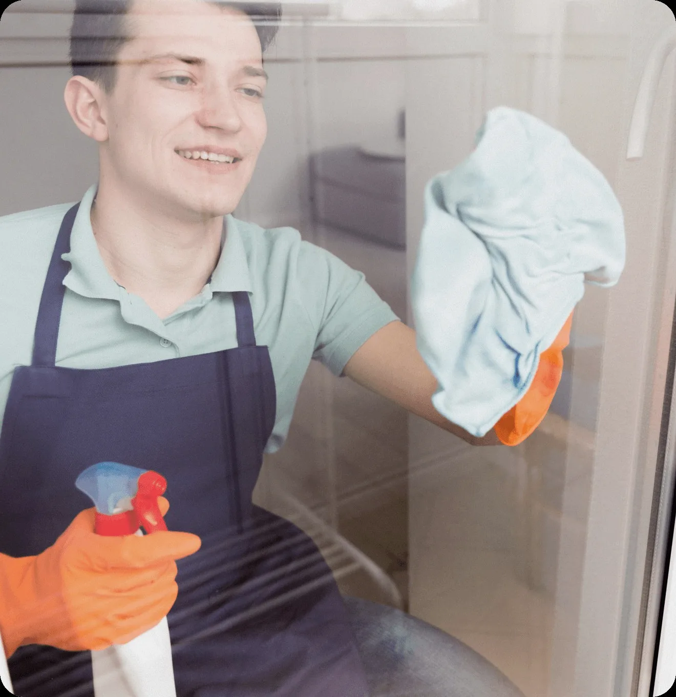 A cleaner in a blue apron wiping a window.