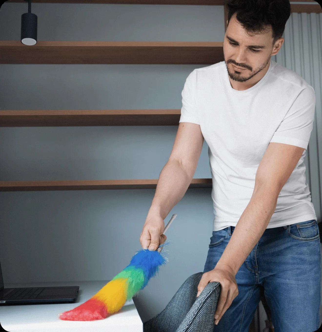 A cleaner dusting a shelf with a feather duster.