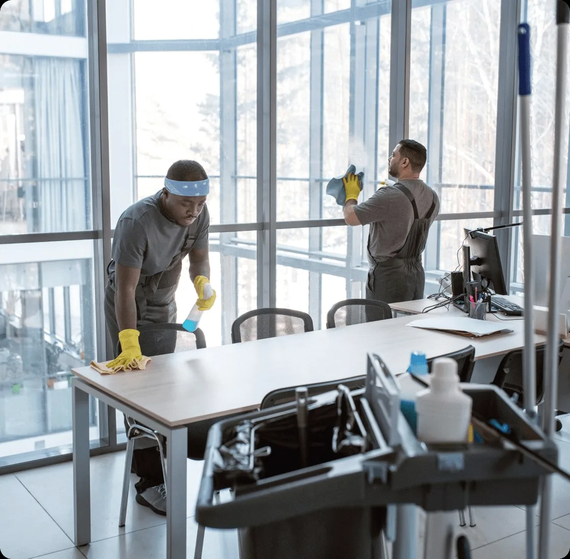 Two cleaners at the windows of a glass office.