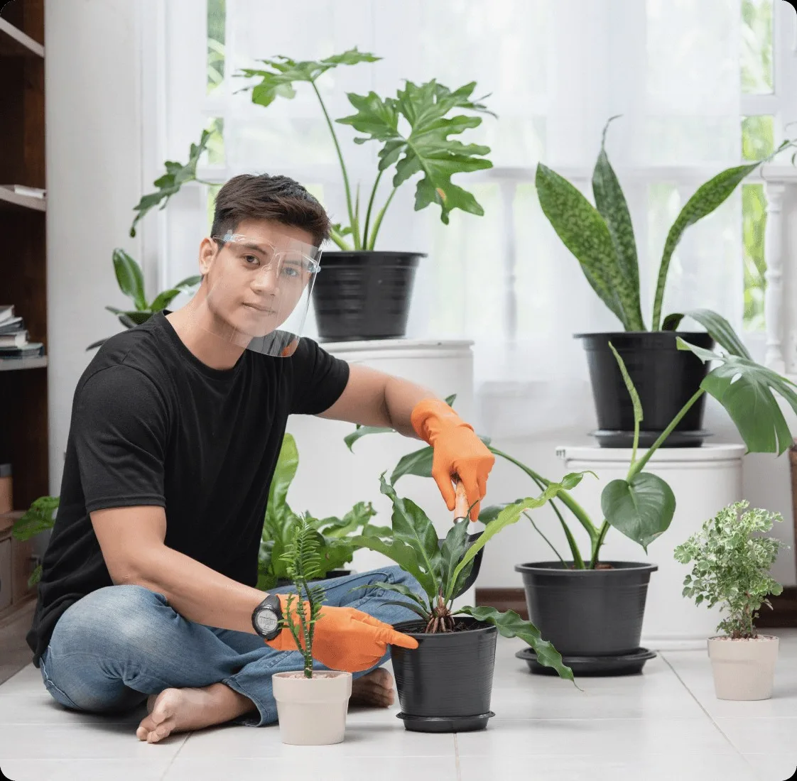 A cleaner in orange gloves among potted plants.