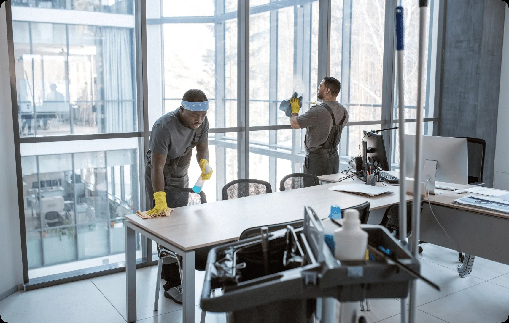 Two cleaners in a glass-walled office.