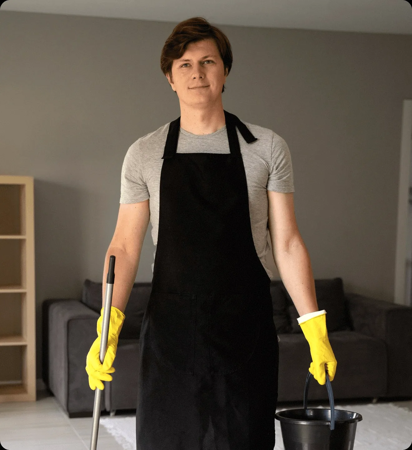 A cleaner in a black apron with a bucket and a mop.