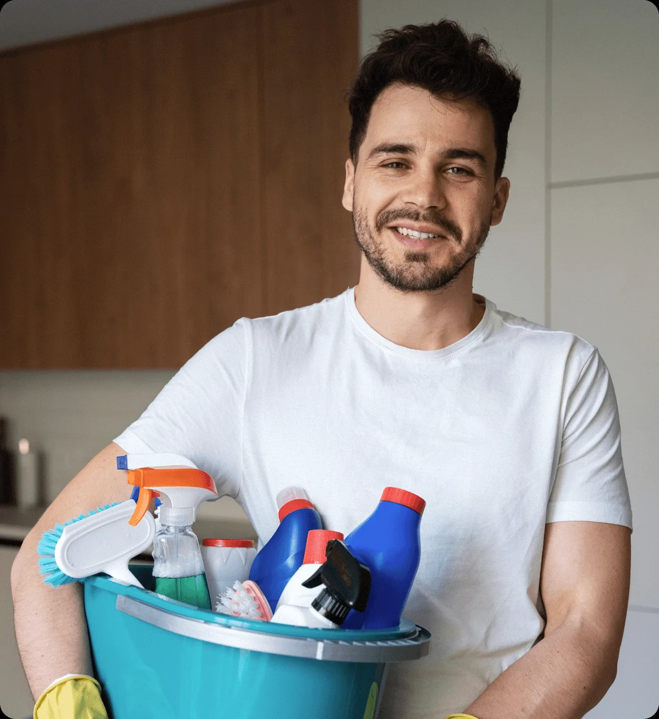 A cleaner holding a bucket of bottles and gloves.