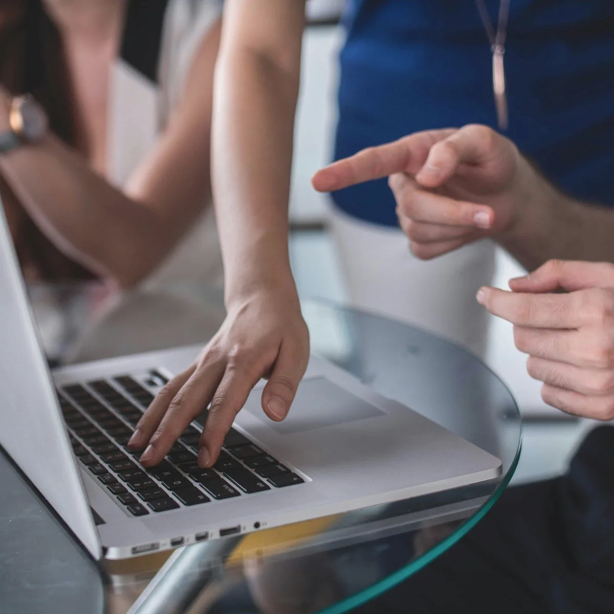 Hands pointing at a laptop screen.