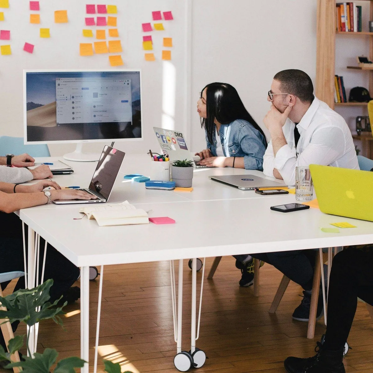 A team at a table under a wall of sticky notes.