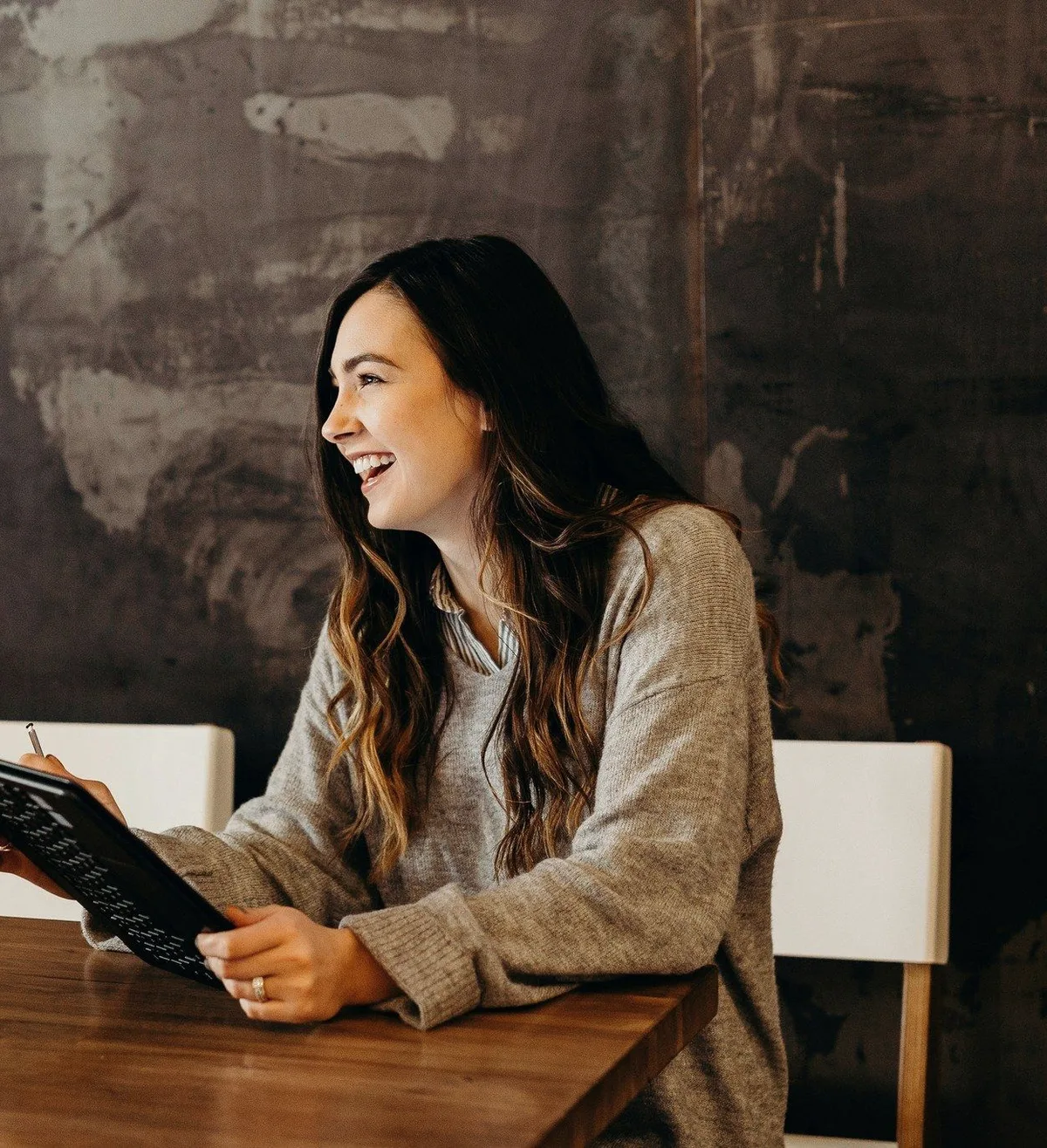 A consultant with a tablet, laughing at a cafe table.