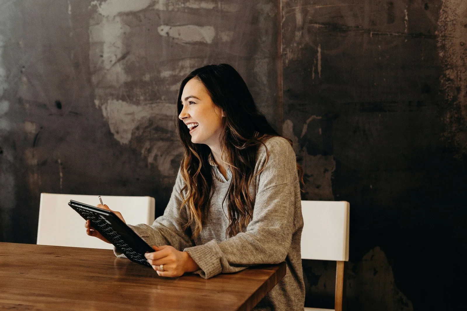 A consultant with a tablet, laughing at a cafe table.