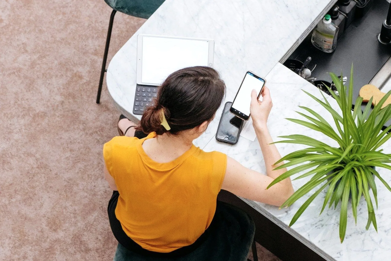 A person in a yellow top at a marble desk, seen from above.