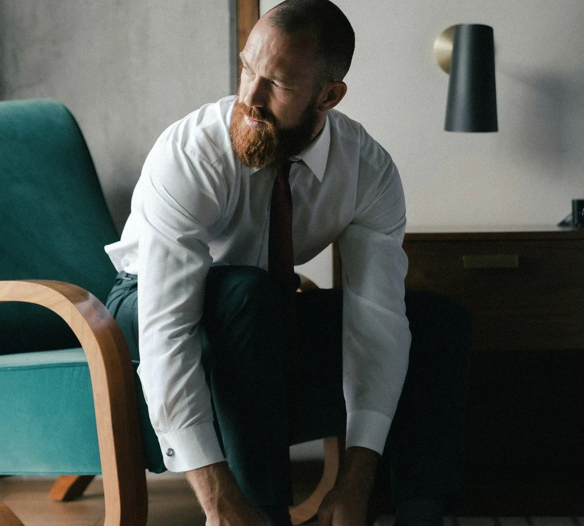 A bearded man in a white shirt leaning forward.