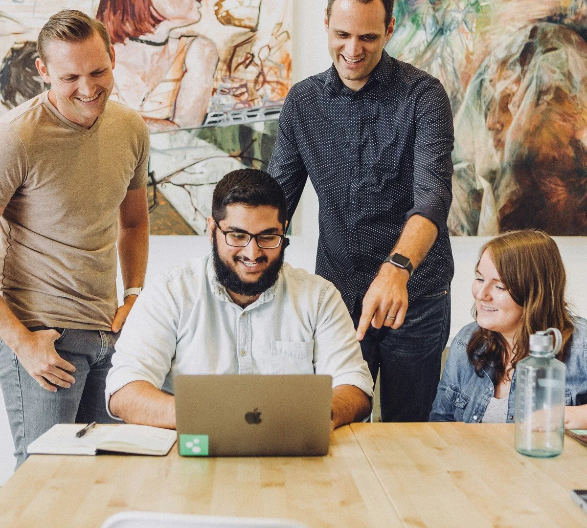 Four colleagues around a laptop.