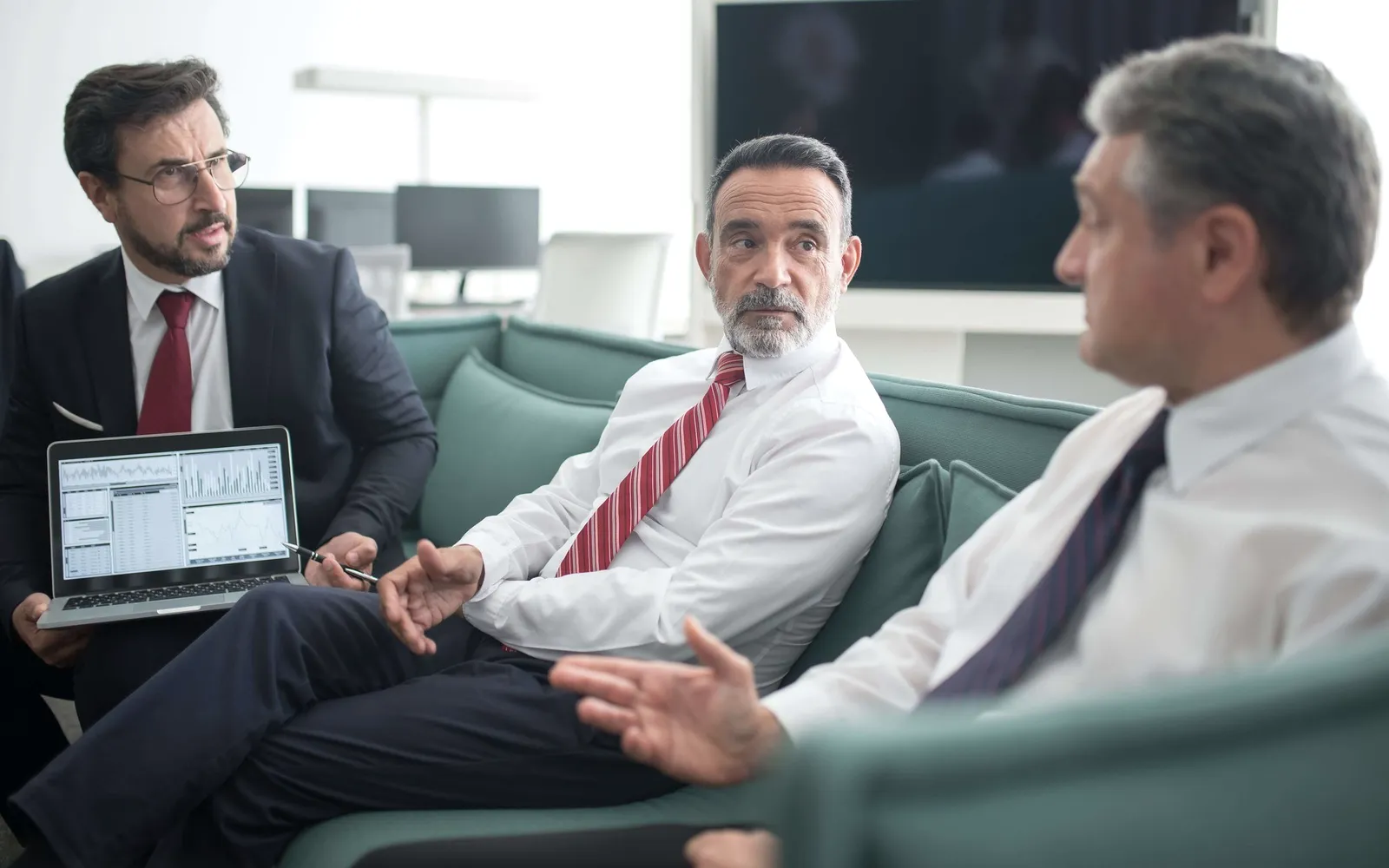 Three men at a table with papers.