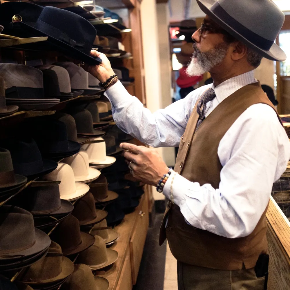 A man in a hat at a shop rail.