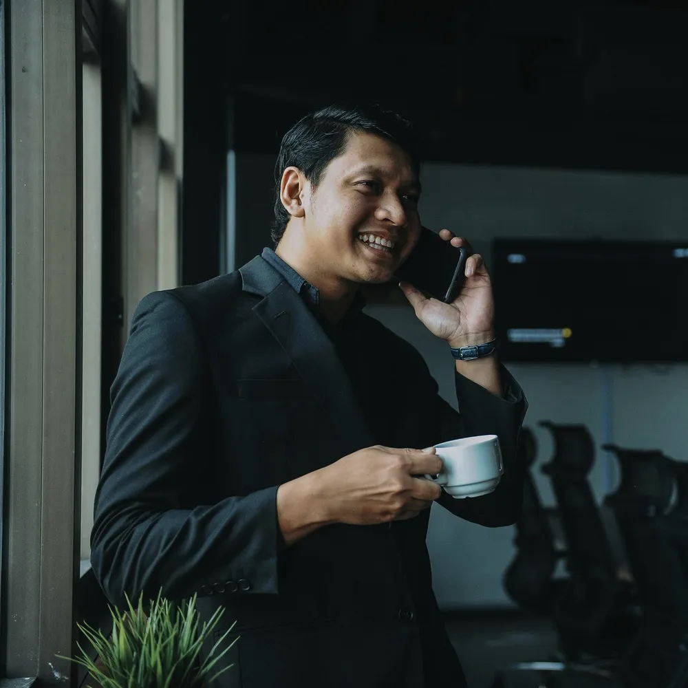 A man on the phone with a coffee.