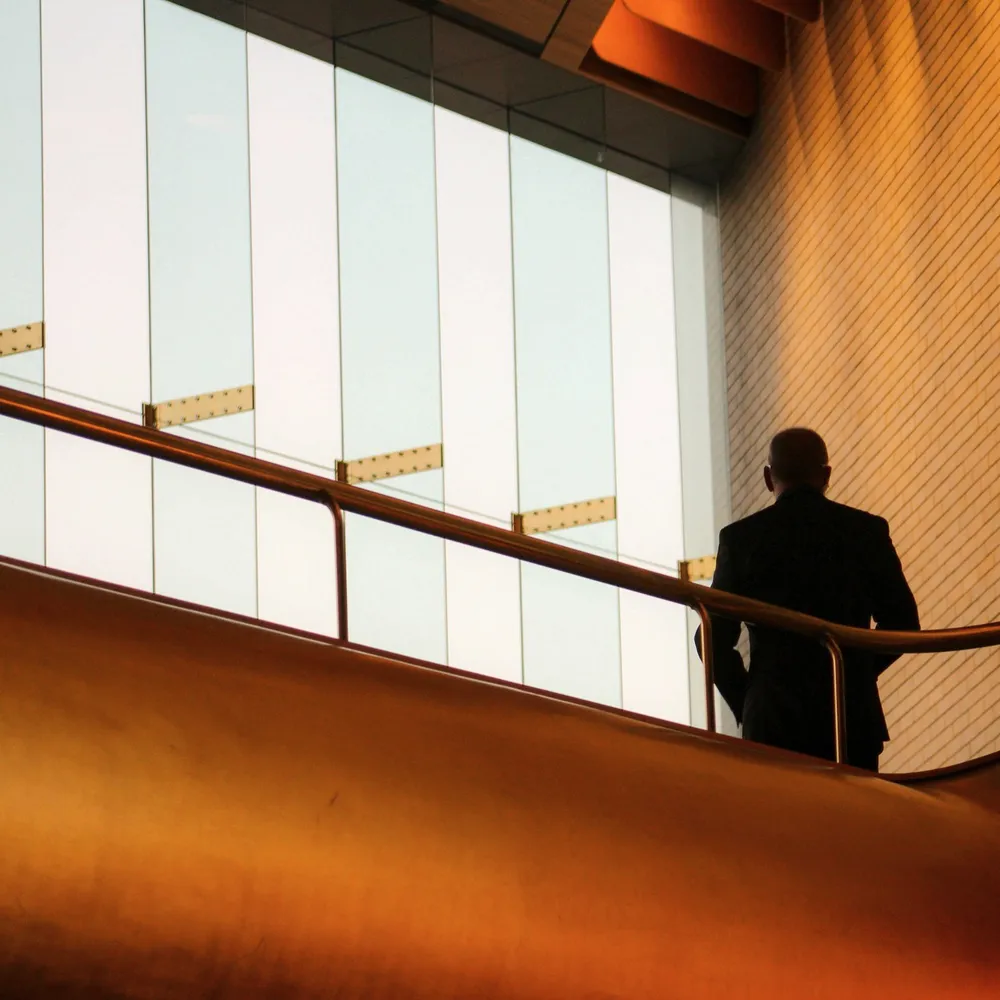 A man at a window in an amber hall.