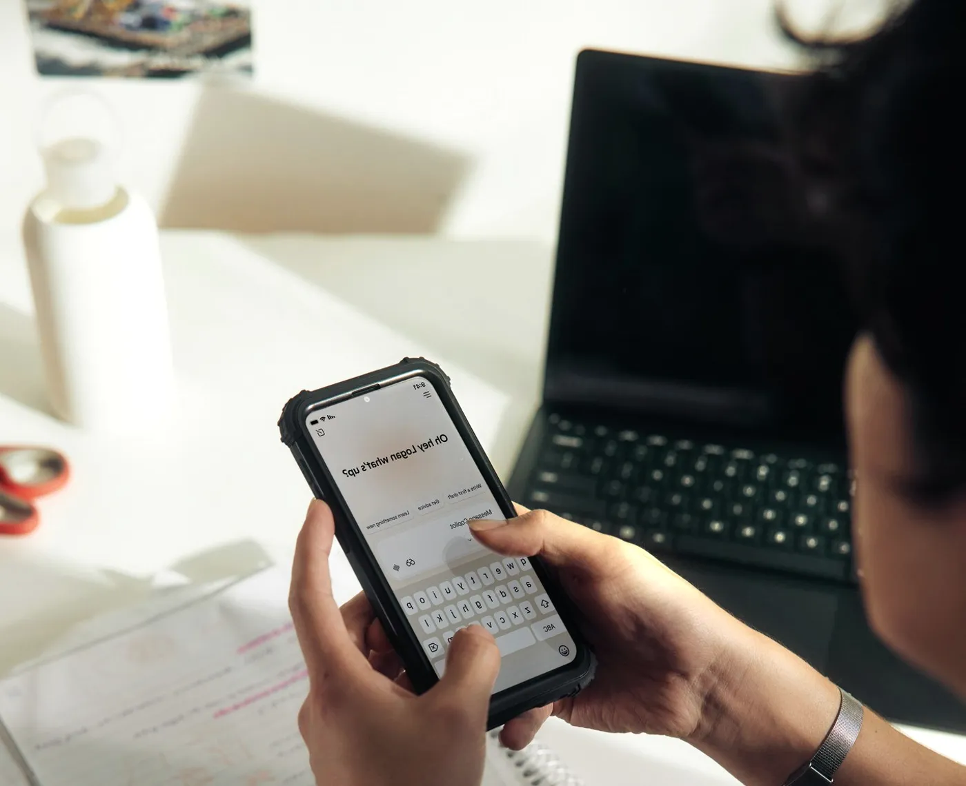 A phone held over a notebook.
