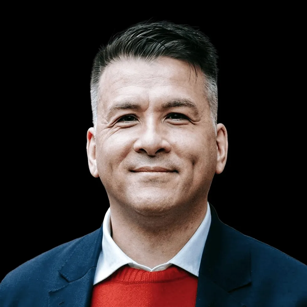 A man in a navy jacket and red jumper.
