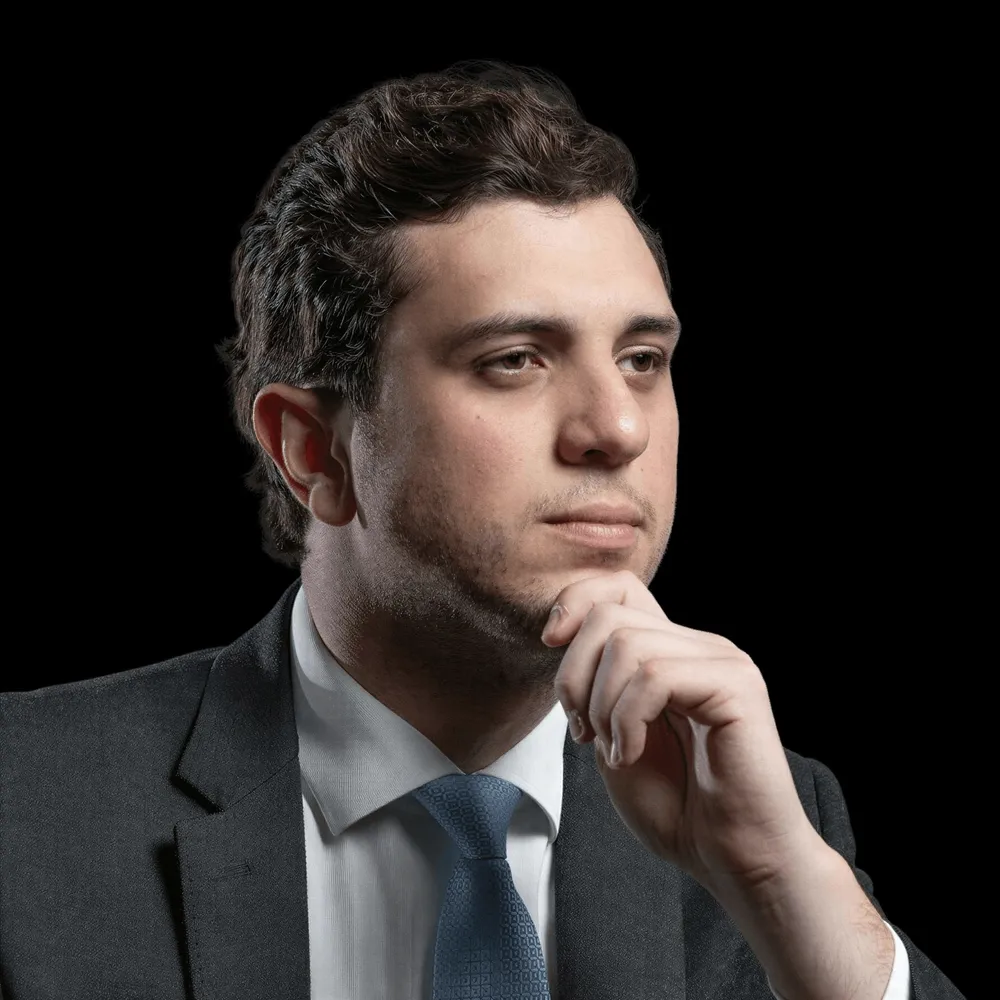 A man in a suit with a hand at his chin.