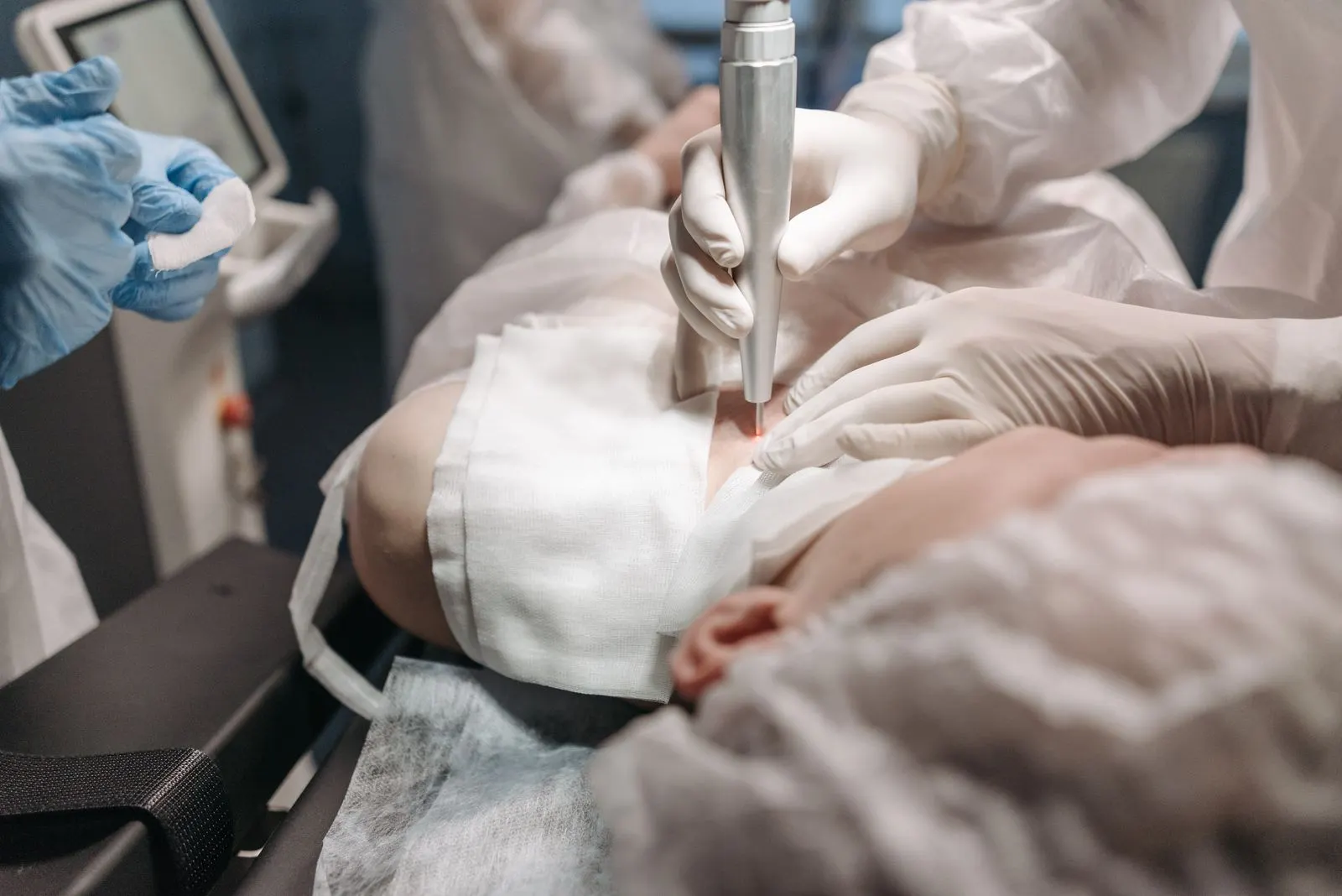 A clinician's gloved hands working with a handheld device, no procedure site in view.