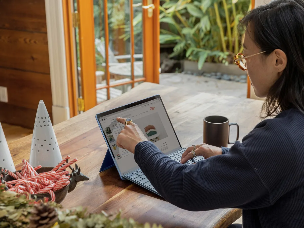 A woman at a laptop by an open window.