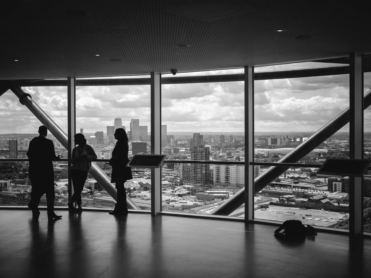People in silhouette inside a glass building.