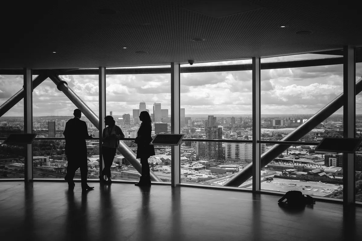 People in silhouette inside a glass building.