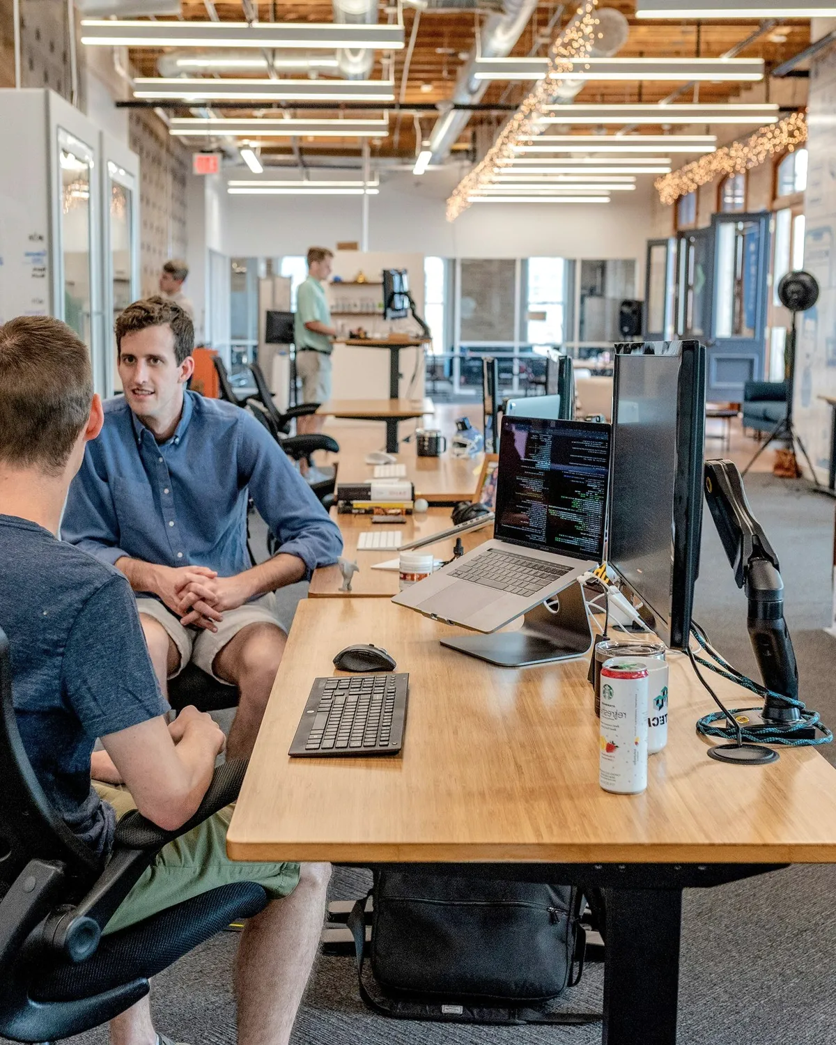 Three men in conversation at a desk.