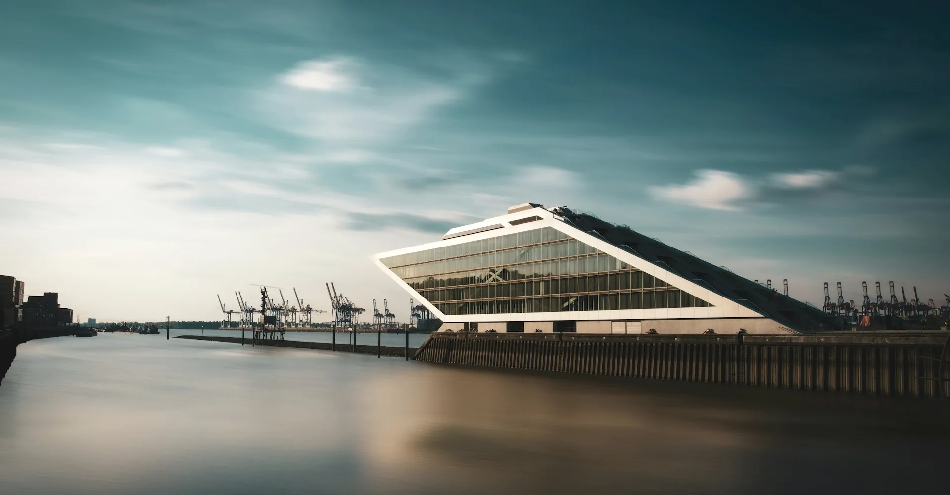 A glass terminal by a harbour at dusk.