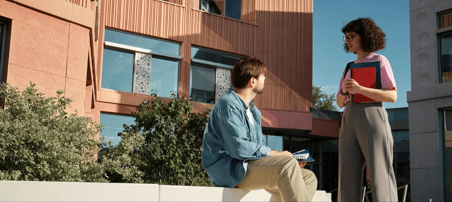 Two students talking on a campus bench.