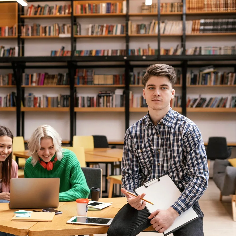 Students at a library table with a laptop.