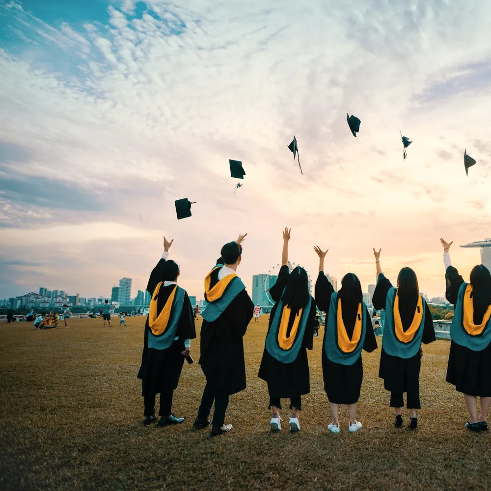 Graduates throwing caps at sunset.