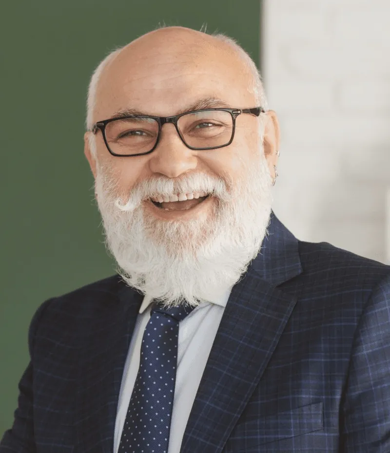 A bearded man in glasses and a suit.