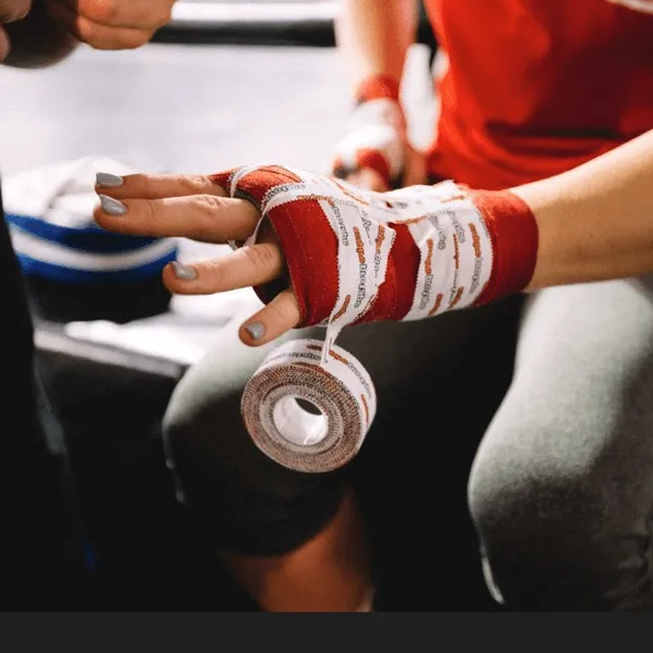Hands wrapping a boxing glove.
