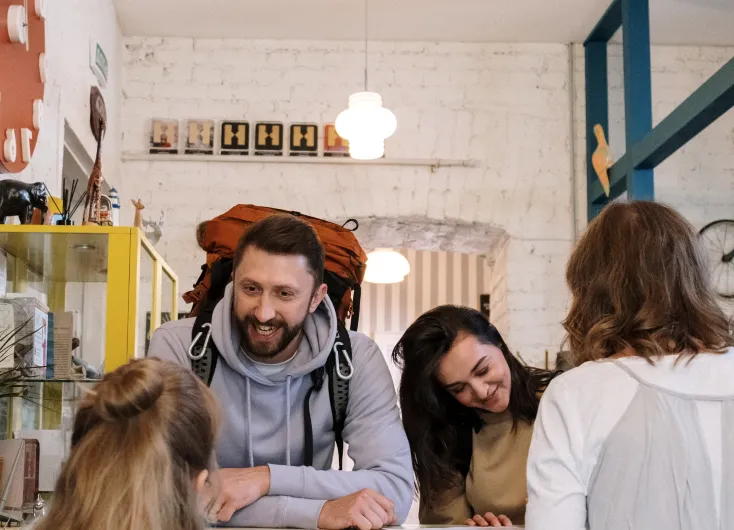 A backpacker laughing with friends at a table.