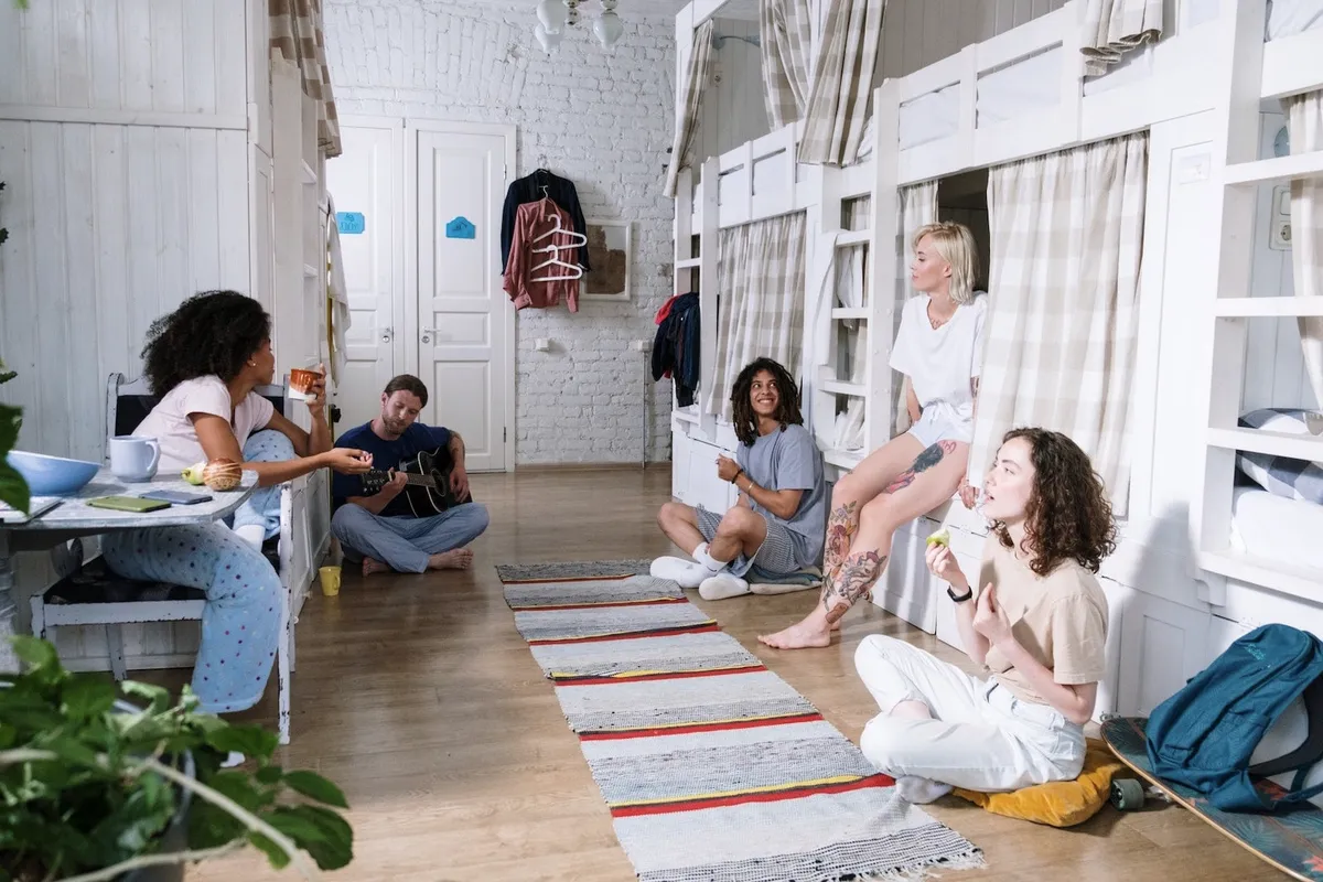 Guests sitting on the floor of a long dorm, talking.