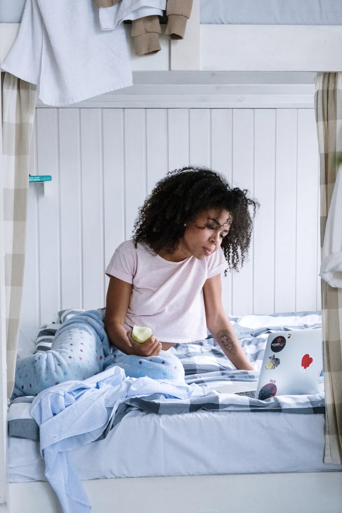 A guest reading on her bunk bed with a laptop.