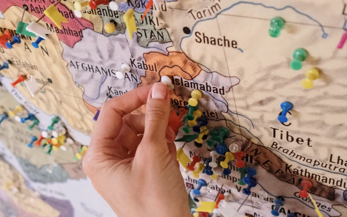 A hand pinning a route on a paper map.