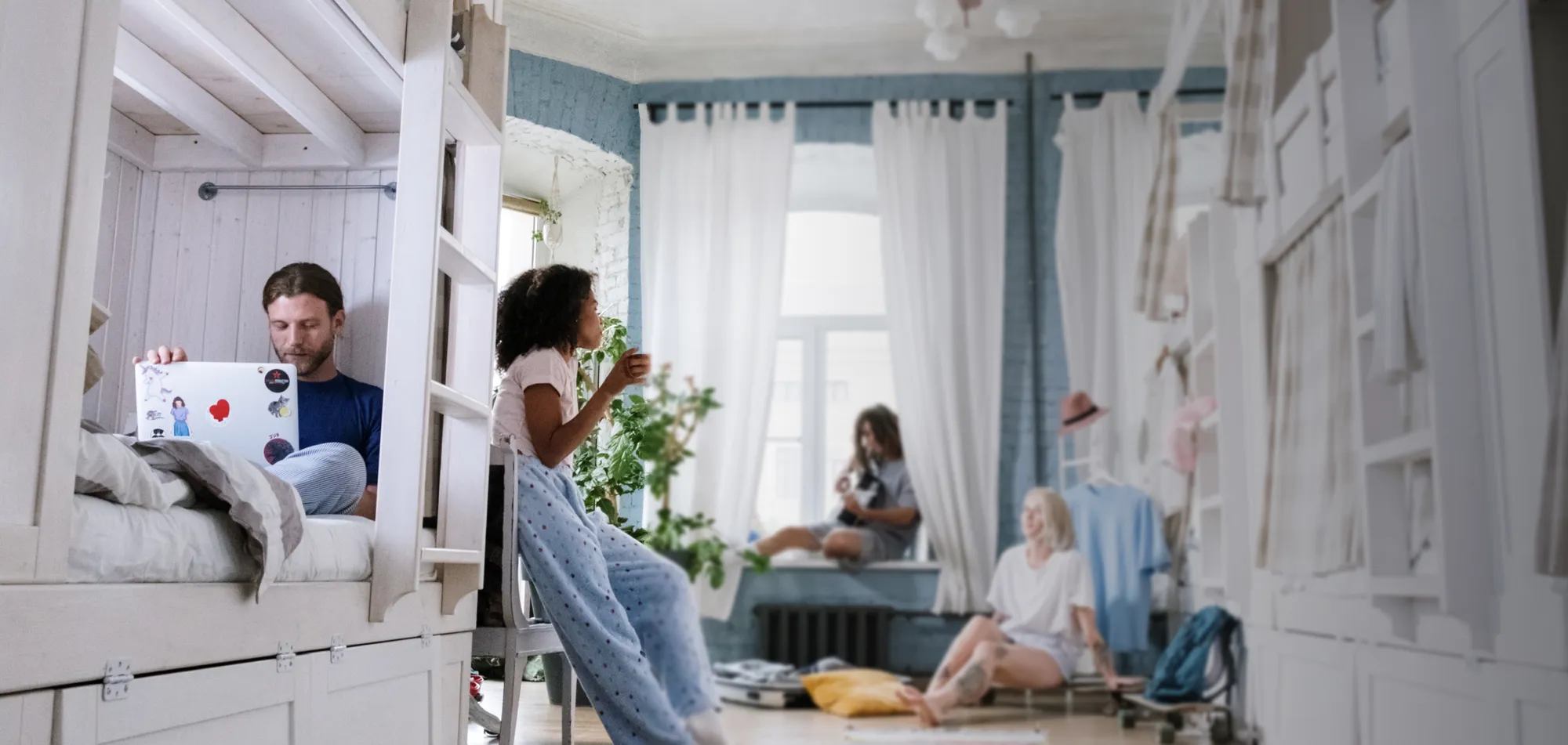 Friends in a sunny dorm with white bunk beds.