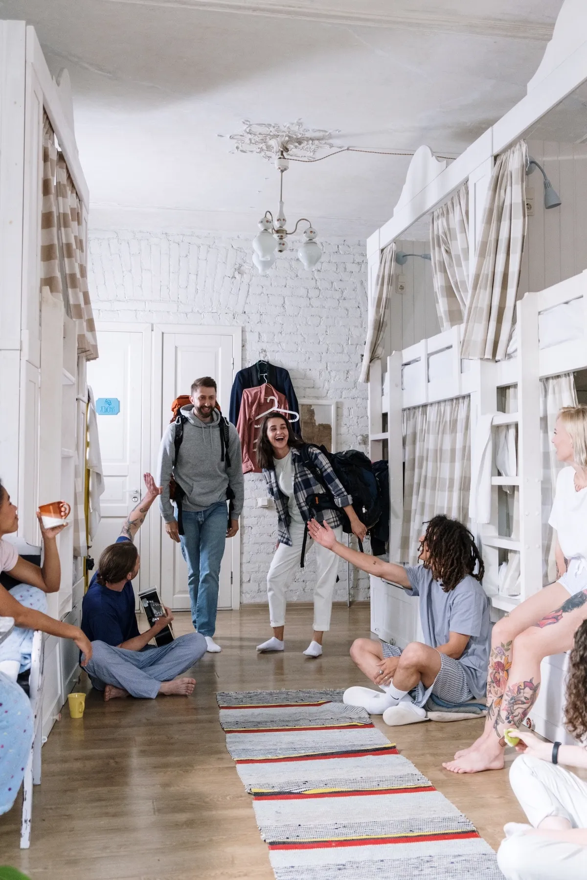 Backpackers meeting in a dorm with white bunk beds.