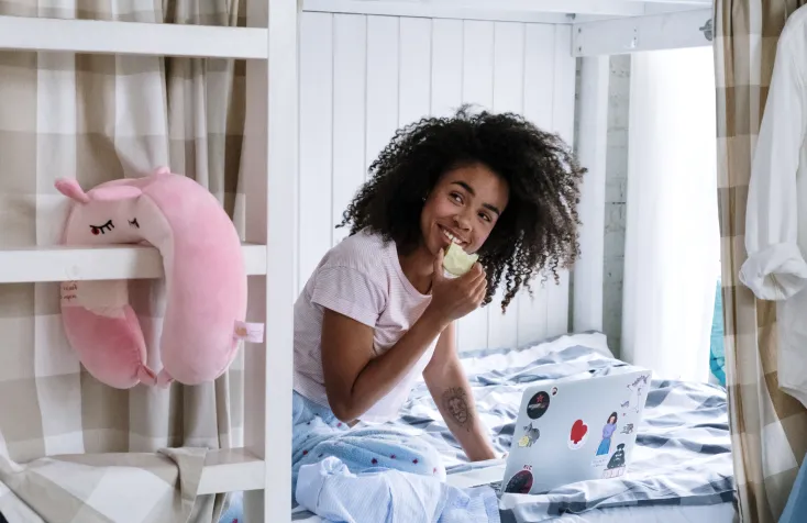 A woman eating an apple on a bunk bed.