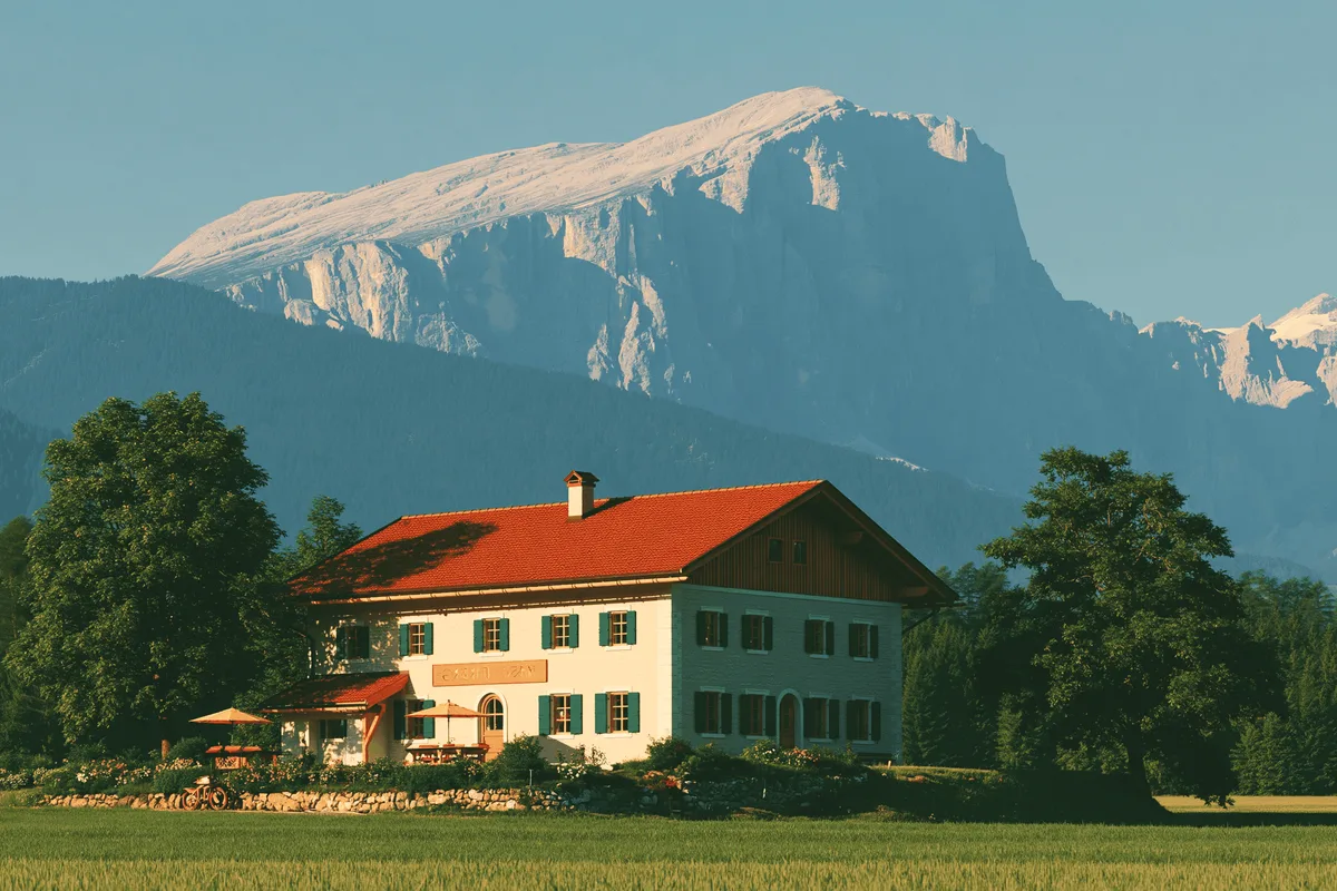 A farmhouse with a red roof under a snowy mountain.