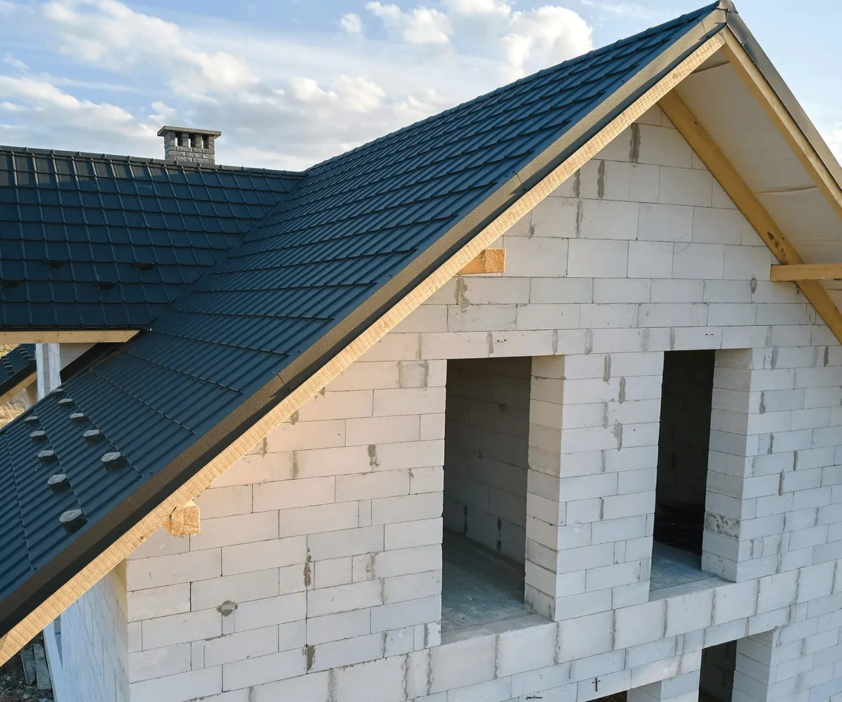A dark metal roof on a block house.