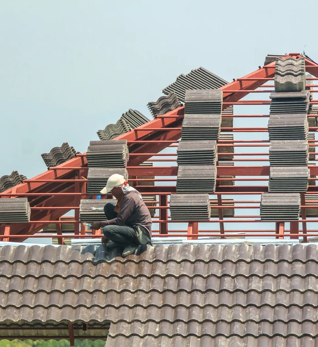 A roofer laying tiles on a red frame.