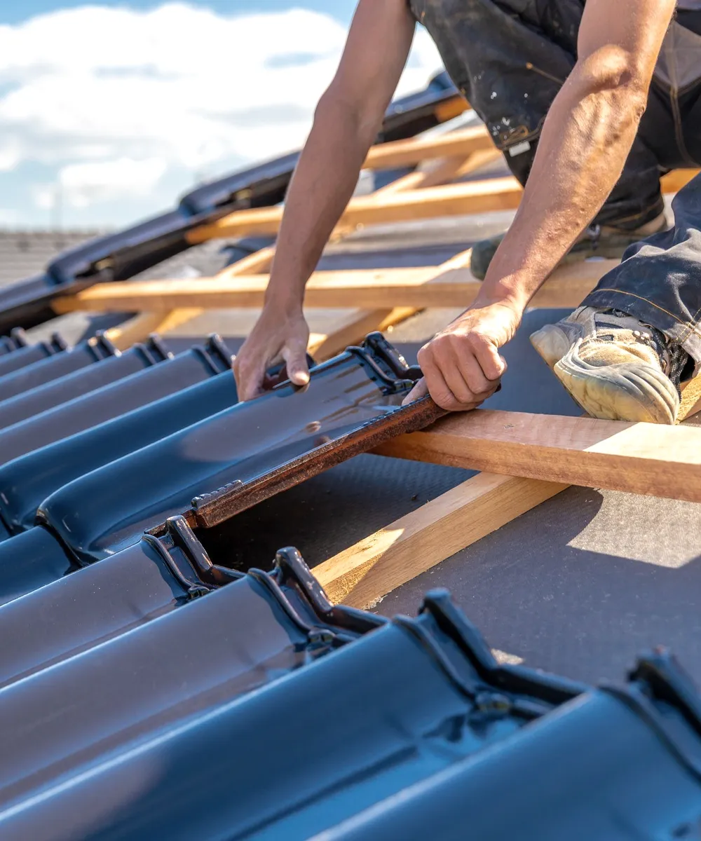 Hands laying blue tiles on battens.